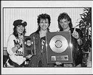 Larry Gowan recruits support from MuchMusic VJs Erica Ehm and J.D. Roberts in order to show off his platinum LP for "Strange Animal" - and gold single "A Criminal Mind". The awards were presented to him prior to the first of three sold out shows at Ontario Place [ca 1985].