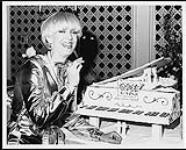 E. Dee Gold standing next to a piano-shaped cake s.d.