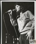 Dianne Heatherington singing into a microphone on a stage [entre 1975-1981].