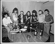"Lead singer and writer Frank Zirone of Hanover Fist has a busy day taking phone calls, signing a world-wide record contract with MCA Records, and colouring the group's first jacket cover. Looking on from left to right are, A&R Director John Alexander, group members David Aplin, Ross Reynolds (who is also Exec. VP & Gen. Mgr. of MCA Records Canada), Chris Brockway and Kim Hunt. Also pictured are  [entre 1984-1985].
