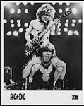 Portrait de presse de deux membres du groupe AC/DC en spectacle (un à la guitare, l'autre étant juché sur ses épaules) [entre 1980-1990].