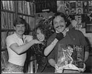 Portrait of Lee Aaron visiting CJAY FM radio in Calgary on a Western tour. Also pictured is Tracey Garbit and Music Director Stewart Meyers [ca. 1984].