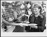 Canadian country music star Carroll Baker signing autographs through a fence. Courtcliffe Park, Hamilton [ca. 1985]
