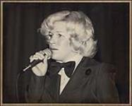 Portrait of Carroll Baker wearing a bowtie singing [entre 1975-1985]