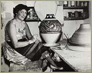 Woman painting a decorative pattern on a large vase [entre 1930-1960].