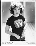 Shirley Eikhard vêtue d'un t­shirt sur lequel il est écrit « As seen on TV » [entre 1972-1975].