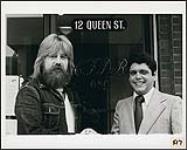 John Ellis en compagnie d'un homme non identifié devant la station de radio CFDR AM, au 12, rue Queen. [entre 1971-1975].