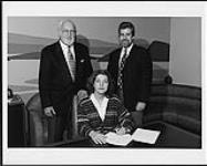 Shirley Eikhard signing a contract in the presence of Deane Cameron and an unidentified man [between 1971-1975].