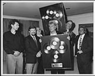 Rod Stewart and Randy Phillips (promoter) receiving album awards for "Out of Order," posed with four unidentified men juin 1989