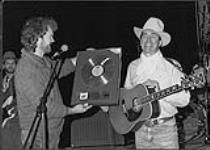 Ian Tyson receiving a Gold album award (Cowboyography) from Holger Petersen of Stony Plain Records [ca. 1986].