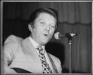 Tommy Hunter singing into a microphone [entre 1968-1975].