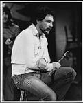 Paul Horn assis sur un banc, une flûte à la main [entre 1970-1973].