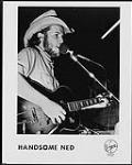 Press portrait of Handsome Ned playing a guitar and singing into a microphone n.d.