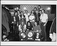 Iron Maiden receiving album awards, posing with a group of people [entre 1983-1989].