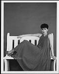 Rita Johns, assise sur un banc, vêtue d'une robe [ca. 1981].
