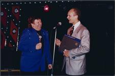 Bobby Curtola et un homme non identifiés parlant au microphone sur scène [entre 1988-1995].