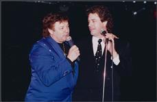 Bobby Curtola et un homme non identifiés parlant au microphone sur scène [entre 1988-1995].