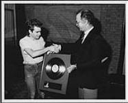 Ross Reynolds, vice-président et directeur général de MCA Records Canada, remet un disque d'or à Nik Kershaw pour son premier 33 tours, « Human Racing » 1984