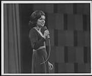 Unidentified woman singing into a microphone [entre 1965-1975].