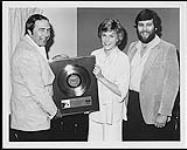 Capitol's Dane Evans (left) and Deane Cameron (right) present Anne Murray with platinum for her New Kind of Feeling album 1979