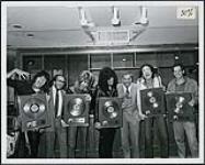 Quiet Riot montrant leurs prix Or canadiens pour avoir fait des ventes supérieures à 50 000 disques pour l'album « Metal Health » [ca 1983].