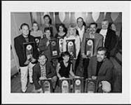 LeAnn Rimes receives multiple awards that are being displayed by Deane Cameron and some unidentified people  [entre 1995-2000].