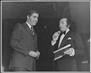 Capitol recording star Al Martino (right) expressing his thanks to Capitol Canada President Arnold Gosewich after the latter had presented him with a Gold record for his single "Volare" on stage at Toronto's Hook & Ladder Club, February 10 [entre 1975-1976].