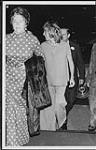 Anne Murray qui marche dans un édifice derrière une femme qui tient un manteau de fourrure [between 1970-1975].