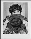 Press portrait of Rita MacNeil hiding her face with a hat [entre 1988-1992].