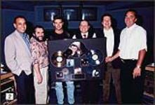 Various record label staffers gather around Roch Voisine as he holds an unidentified award [entre 1993-1994].