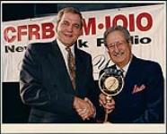 Ted Woloshyn and Walter Crouter in front of a CFRB banner [entre 1996-2000].