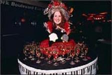 A woman dressed in a costume serving glasses of wine [between 1990-2000].