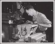 Homme faisant fonctionner de la machinerie dans une usine [between 1955-1965]