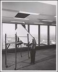 Deux hommes installent des carreaux de plafond à la Place Ville-Marie. Montréal, octobre 1962 octobre 1962