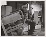 Un homme dont l'identité est inconnue fabrique un meuble [entre 1930-1960]
