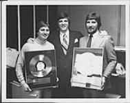 Gaston Gravell and two unidentified men holding awards [entre 1979-1982].