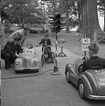Des enfants conduisent des voitures miniatures sur un parcours 1955