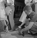 Pail Brisbois (à gauche) et le prospecteur Cy Ross tenant un a radiomètre au-dessus d'une piste de danse 1955
