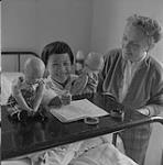 Nurse Irene Moore helps a young leprosy patient 1957
