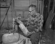 Un vieil homme [Mungo Martin] travaillant à une sculpture en bois 1955