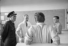 Le gardien K. McKenzie, à gauche, l'instructeur D. Franklin, au centre, et l'agent du personnel Dave Barrett, à droite, parlent avec un détenu 1958