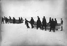 Des hommes déplaçant un bateau sur la glace, le seul moyen d'accès au continent avant les traversiers de la Confédération 1958