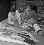 David et Jennifer Webber examinant des cartes et des documents en préparation à la construction d'une maquette d'un terrain de bataille 1959