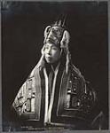 [Studio portrait of Ken-Nah-Gah, Tlingit woman from Yaakwdáat, dressed in naaxein (Chilkat blanket) and headdress worn for potlatch ceremony]. Original title: Klen-Nah-Gah, Yakutat native in full potlatch costume [ca. 1906]