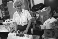 Woman standing in front of empty produce boxes at food bank August-September 1990