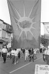 Close-up view of Mohawk Warrior Society flag flying over crowd marching in street 11 July 1995