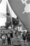View of crowd marching on street with man at front holding up Mohawk Warrior Society flag 11 July 1995