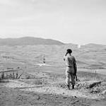 Engineers blow a mine along road below castle as Sgt. Z. Buchsbaum watches. The Sgt. was with British Army four years in North Africa, now attached to 2 C.I.B. as an interrogator. (speaks Italian) 1943