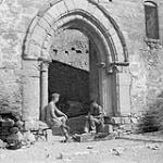 Pte. J. Hubic gives a shoe to Pte. R.J. Edwards to repair in archway of 13th Century Castle which is Coy HQ for PPCLI at Castel Lagopesole 1943