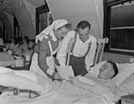 Canadians in England. Lt. N/S Natalie Pope, watches on left as Pte. Robert Barr centre the ward salesman sells a bond to Pte. Leslie Pool. Pte. Poole has a broken leg and Pte. Barr the salesman in his ward has had his left foot amputated 16 October 1944.